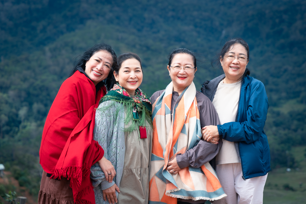 4 c&ocirc; phụ nữ của c&ocirc;ng ty MayQ chụp ảnh tr&ecirc;n đồi Kon Tu Ma trong tour 1n1d trekking camping măng đen đứng chụp ảnh với đồi n&uacute;i v&agrave; rừng c&acirc;y ph&iacute;a xa