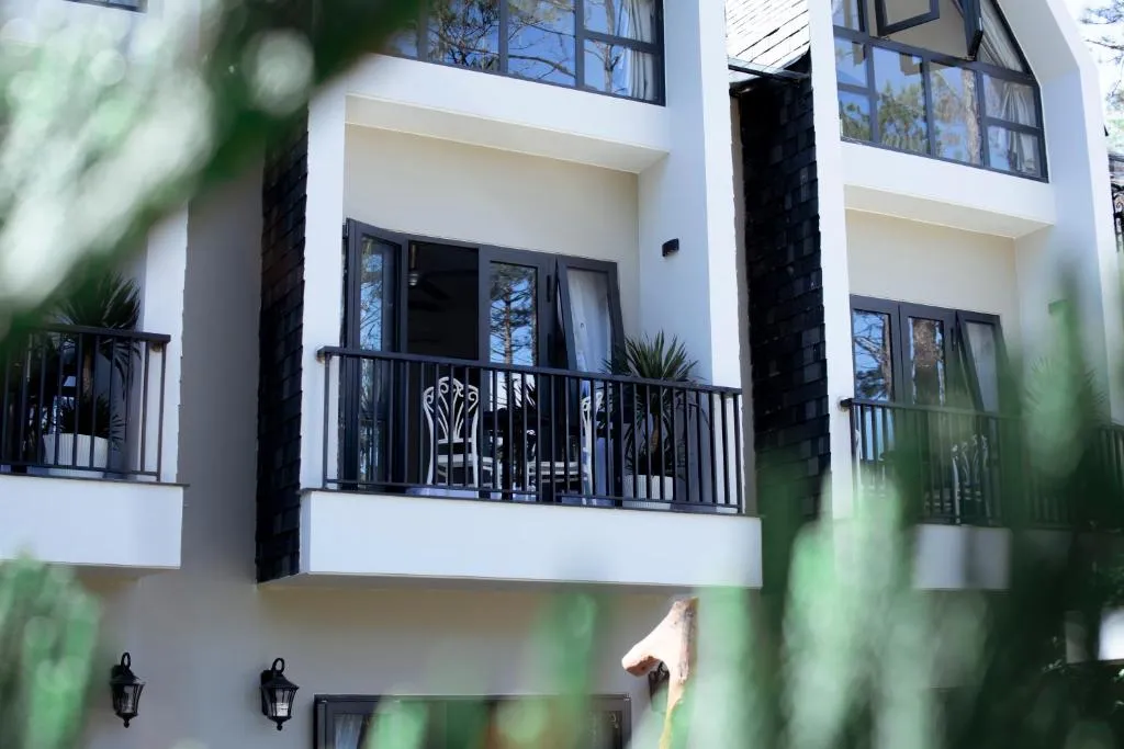 Mặt ngoài Casa Vanilla Măng Đen với ban công trắng giữa tán thông, gợi ý khách sạn đẹp ở Măng Đen cho cặp đôi