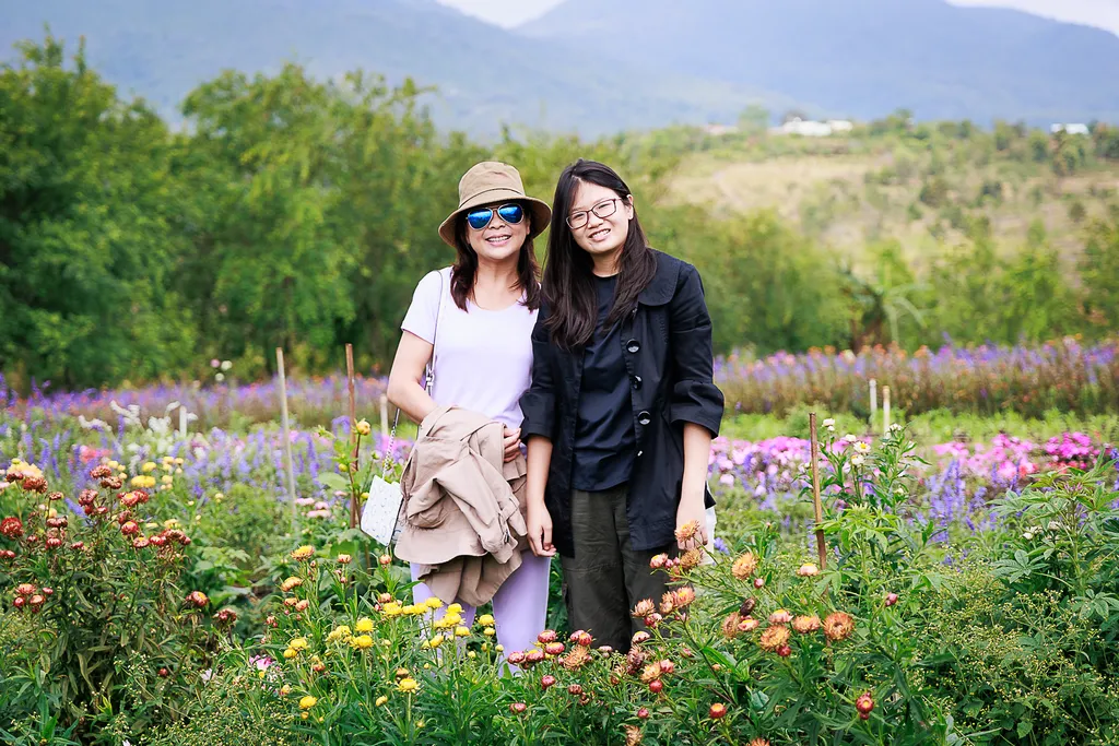 Hai du kh&aacute;ch chụp ảnh giữa vườn hoa v&agrave; nền n&uacute;i tại Thiện Mỹ Farm Măng Đen