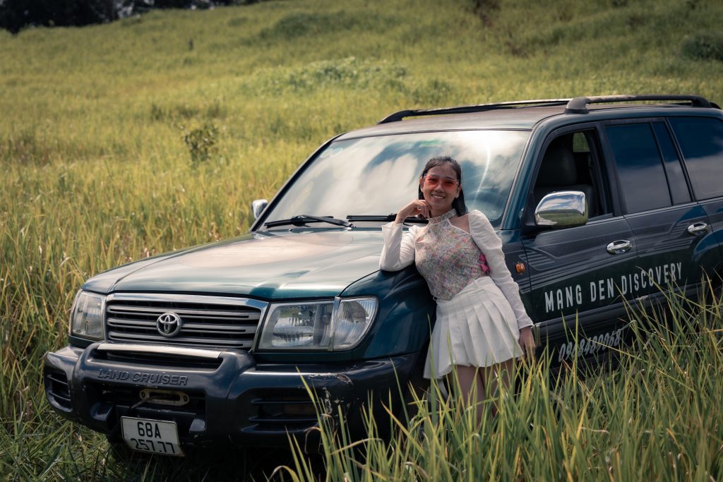 cô gái tạo dáng bên xe 2 cầu của Măng Đen Discovery tại đồi cỏ khi tham quan tour tham quan măng đen