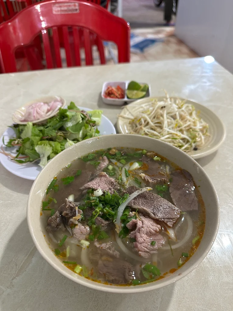 T&ocirc; phở nước b&ograve; tại Qu&aacute;n B&agrave; Bảy Măng Đen ăn k&egrave;m rau sống v&agrave; h&agrave;nh ng&acirc;m